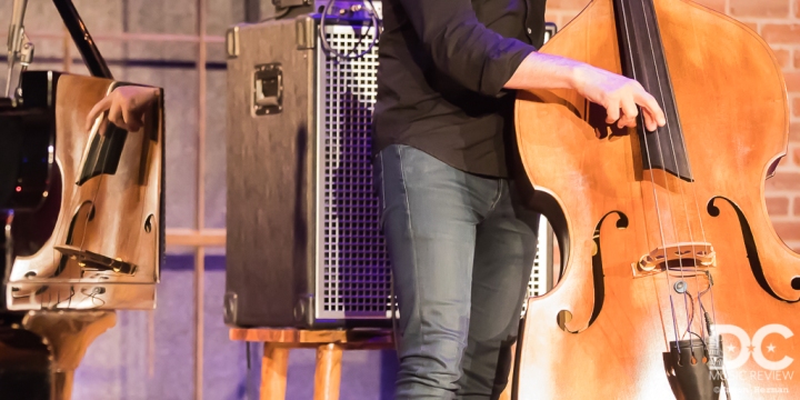 A portrait of Reid Anderson and his bass as reflected off of  Orrin Evans's piano.